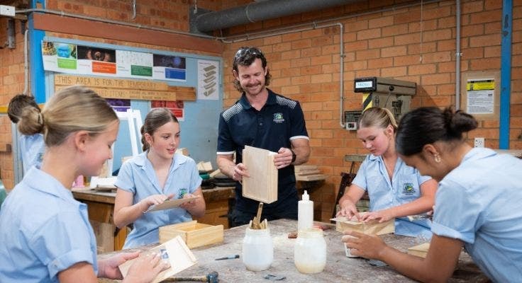 Teacher assisting junior students in woodwork class